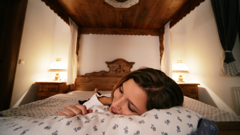 Vacation in the Weinviertel, © Weinviertel Tourismus GmbH / Weinfranz Woman sleeping in a cozy four-poster bed.