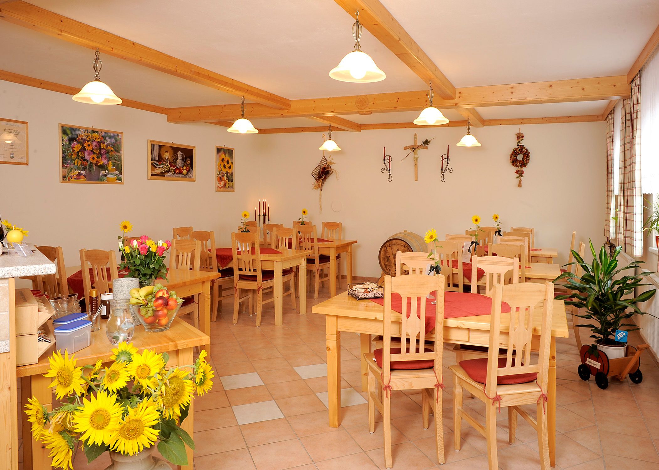 Ein gemütlicher Frühstücksraum mit Holzmöbeln, Sonnenblumen und Dekorationen an den Wänden.