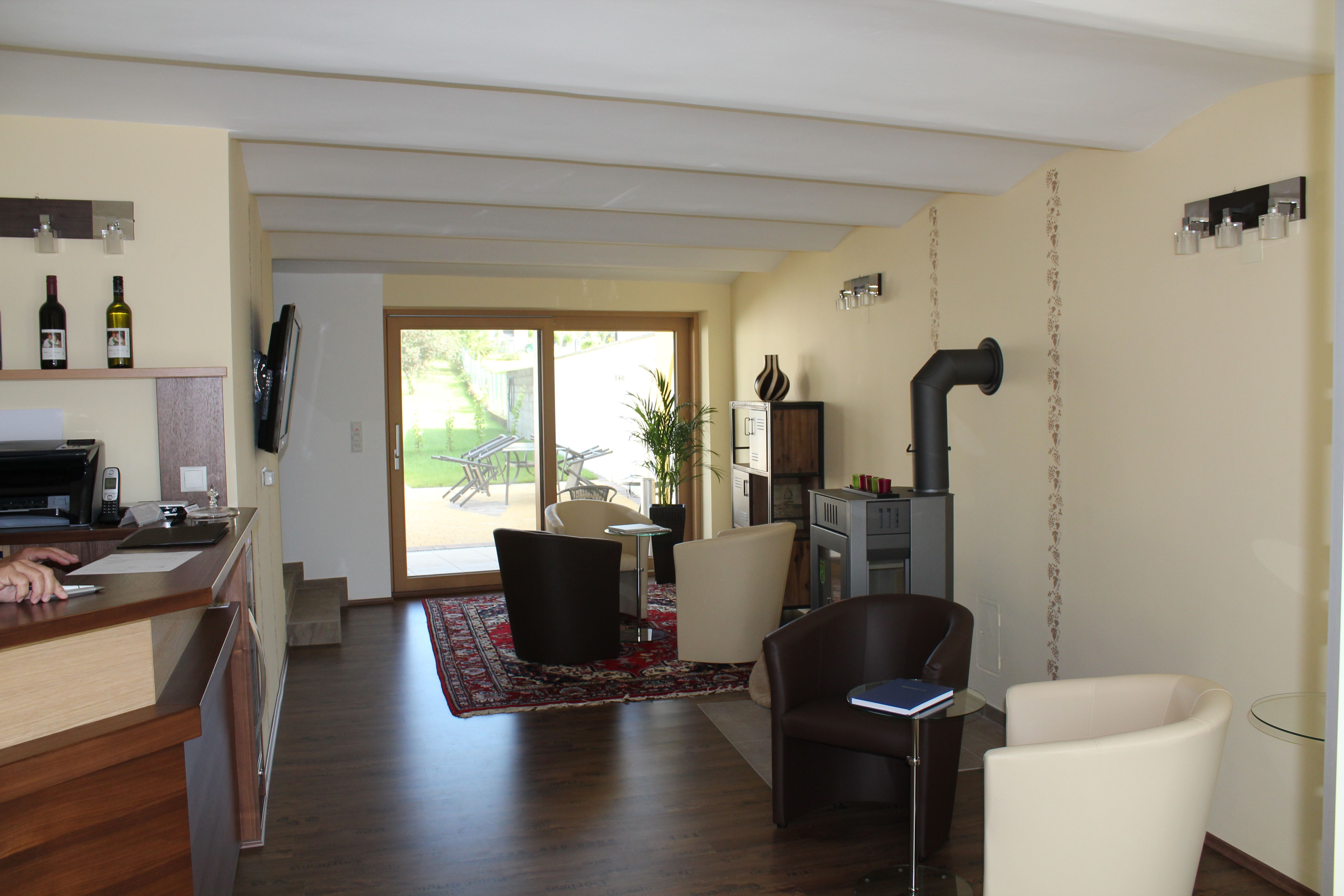 Innenansicht eines modernen Gästehauses mit Sitzbereich, Kamin und Glastür zum Garten.