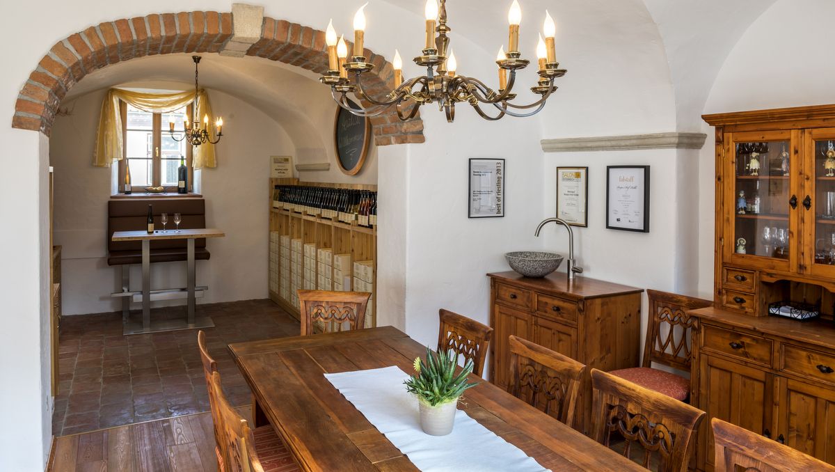 Gemütlicher Raum mit Holzmöbeln, Kronleuchter und Weinregal.