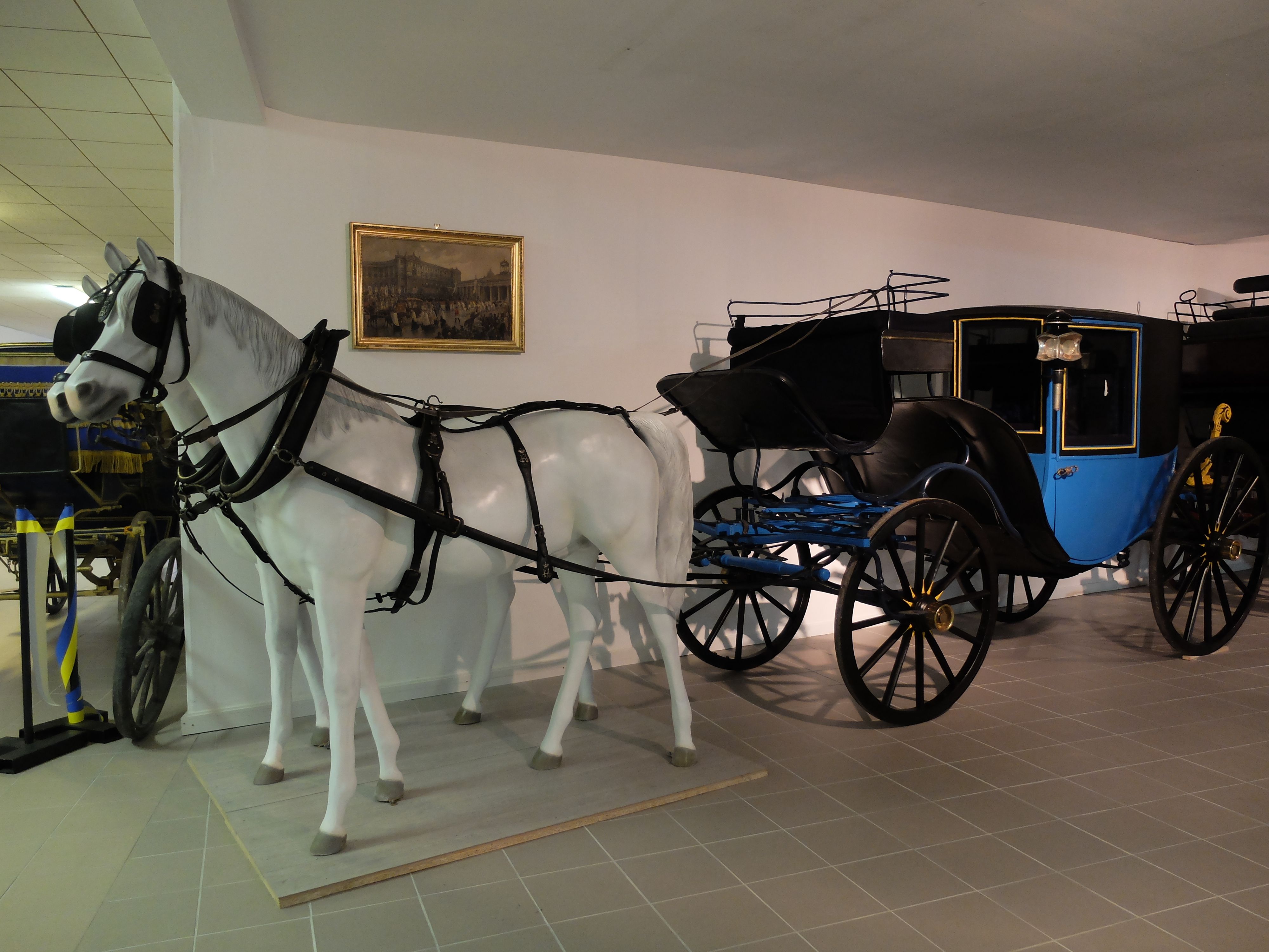 Eine historische Kutsche mit einem weißen Pferdemodell in einem Museum.