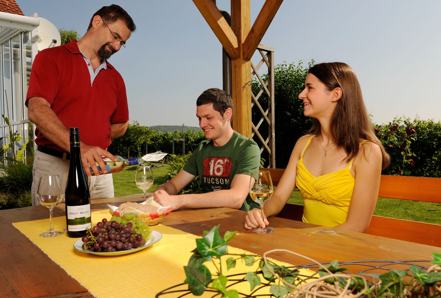 Ein Mann schenkt Wein für zwei Personen an einem Tisch im Freien ein.