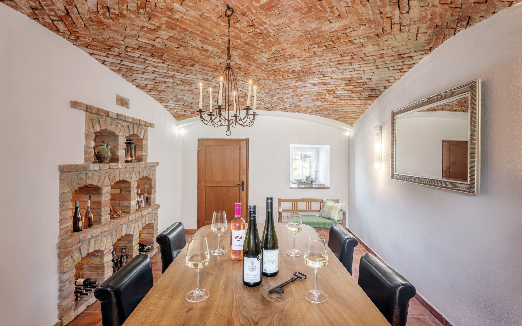 Cozy wine cellar with brick vault, wooden table, wine glasses and bottles.
