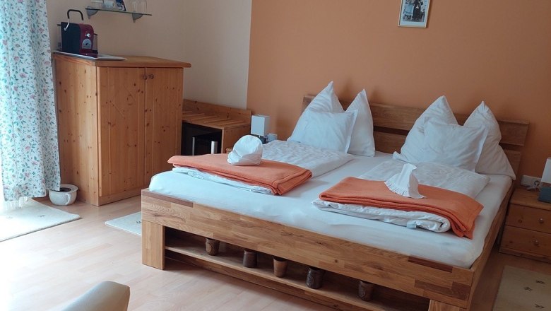 Gem&uuml;tliches Schlafzimmer mit Doppelbett, Holzm&ouml;beln und oranger Wand.