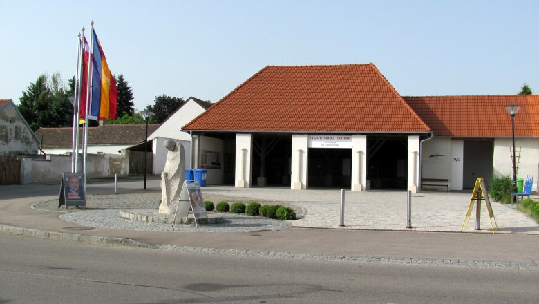 Außenansicht des Ziegelmuseums in Ziersdorf mit roten Dachziegeln und Flaggen.