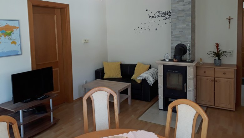 Wohnzimmer mit Kamin, Sofa, Tisch und Fernseher.