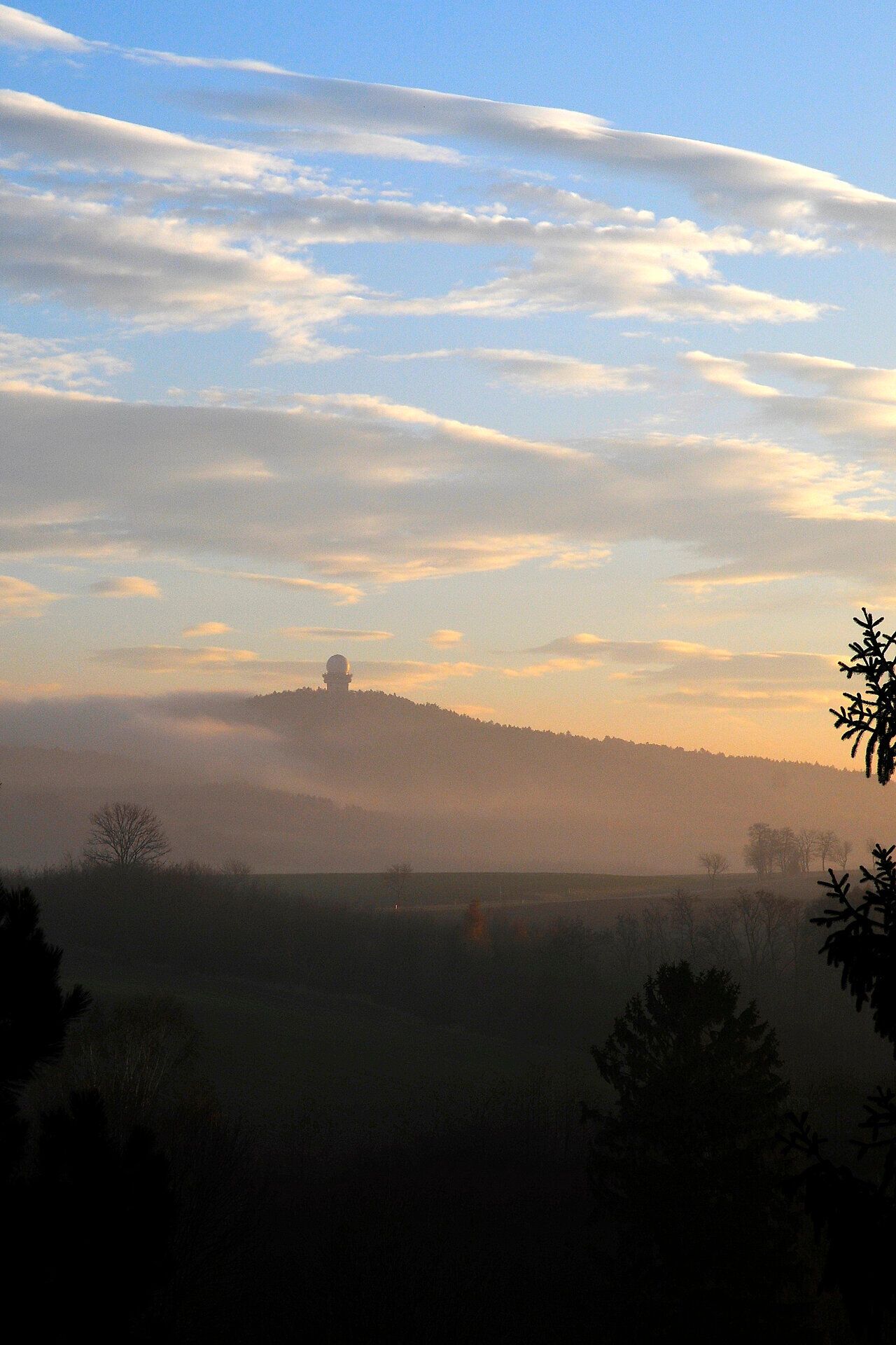 Die sanften Hügel des Buschbergs sind in ein zartes Morgenlicht getaucht, während der Nebel sanft über die Landschaft zieht. Die ruhige Atmosphäre lädt dazu ein, die frische Bergluft zu genießen und die Schönheit der Natur zu erkunden.