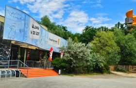 Eingang der Fossilienwelt mit einem großen Banner und Bäumen im Hintergrund.