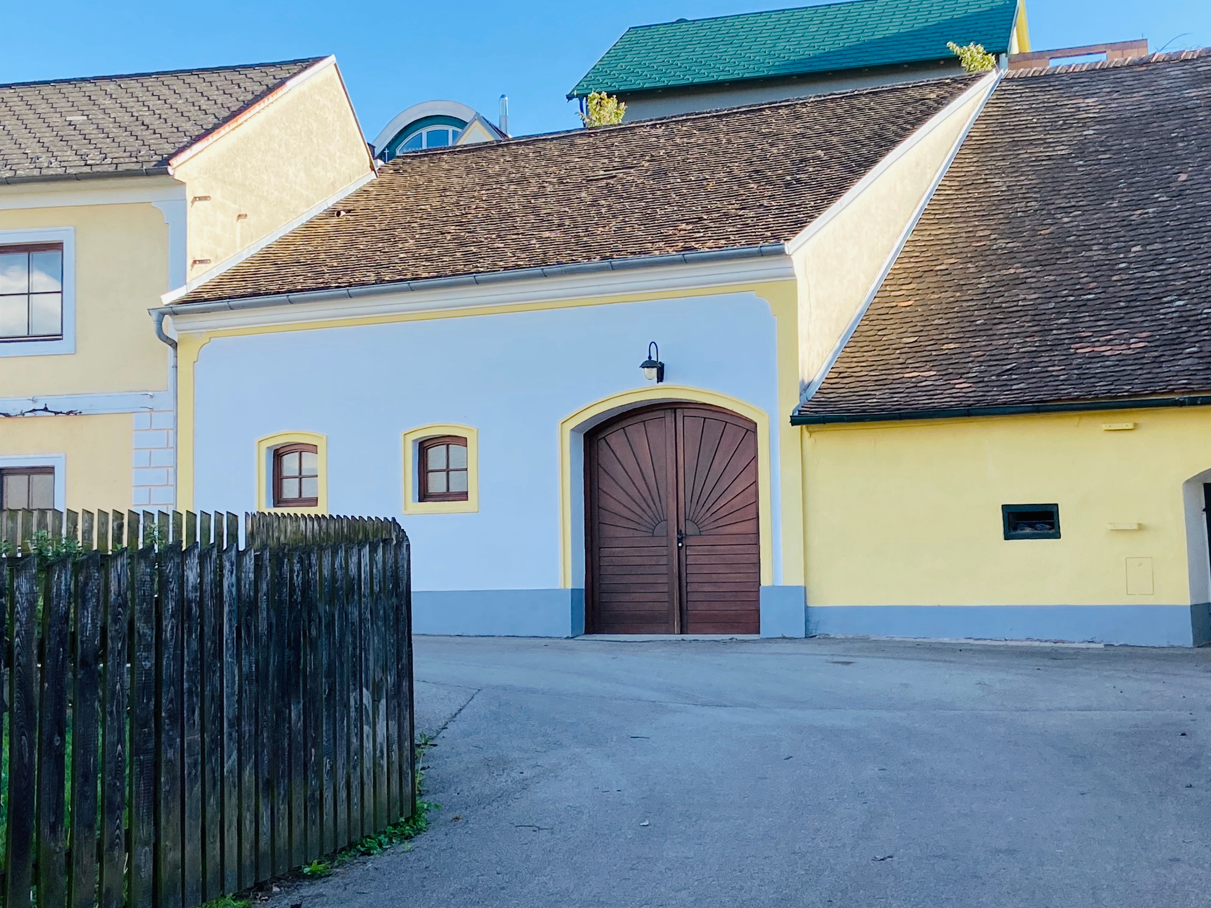 Gelbes Gebäude mit Holztor und Schindeldach in Deinzendorf, Weinviertel.