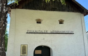 Eingang des Pulkautaler Weinbaumuseums mit alten landwirtschaftlichen Ger&auml;ten davor.