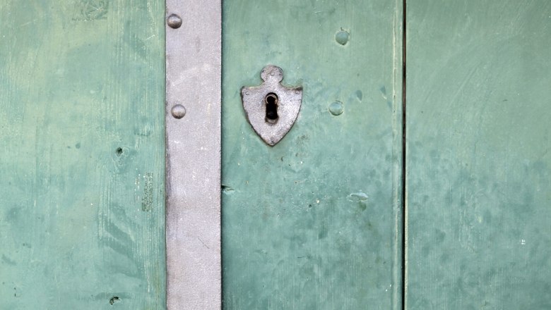 Green wooden door with metal fittings and a keyhole.