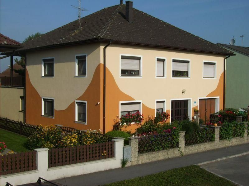 Zweistöckiges Haus mit orange-beiger Fassade und Garten.