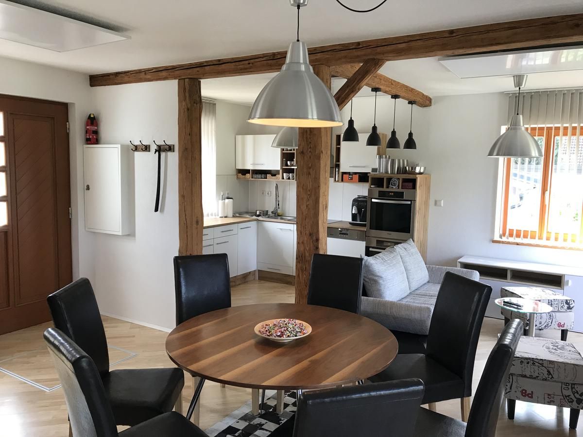 Moderner Wohnbereich mit Esstisch, Stühlen, Küche und Sofa.