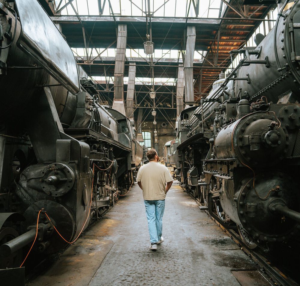 Zwischen den majestätischen Dampflokomotiven des Heizhauses entfaltet sich eine nostalgische Atmosphäre, die die Geschichte der Eisenbahn lebendig werden lässt. Der sanfte Klang der Schritte auf dem alten Boden und der Duft von Eisen und Öl laden dazu ein, in vergangene Zeiten einzutauchen und die Faszination der Technik zu erleben.