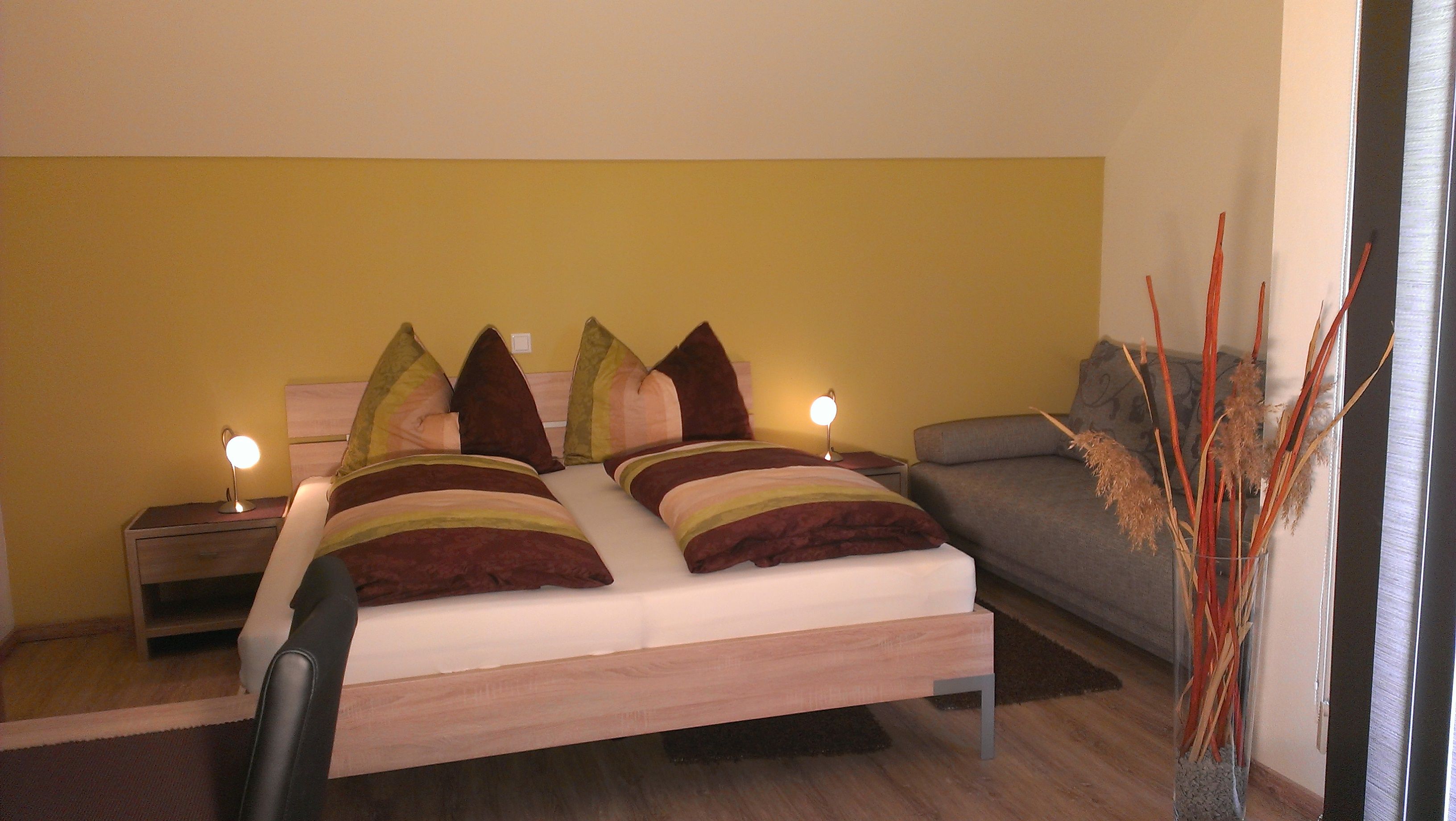 Gemütliches Schlafzimmer mit Doppelbett, Sofa und Dekoration.