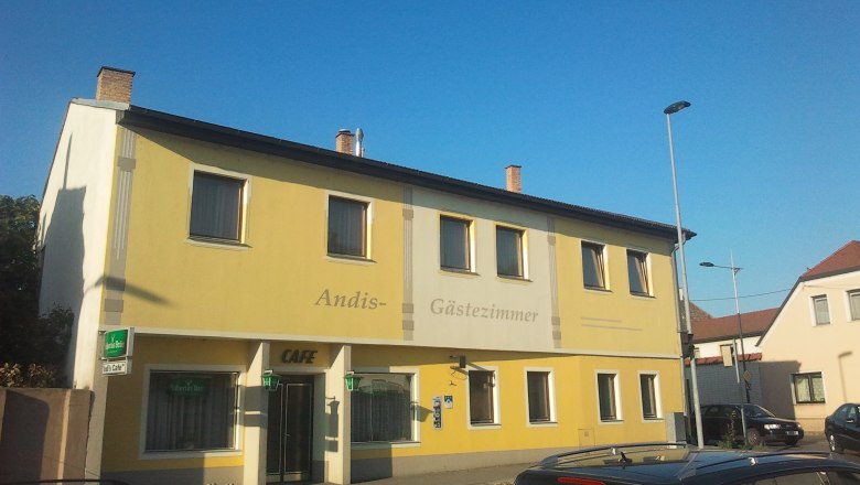 Gelbes Geb&auml;ude mit der Aufschrift 'Andis G&auml;stezimmer' und 'Cafe'.
