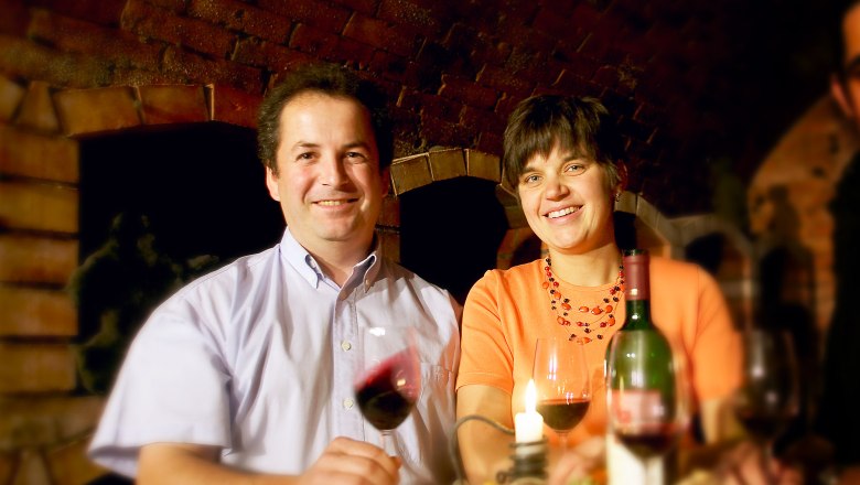 Ein Mann und eine Frau sitzen an einem Tisch mit Wein und Kerze.