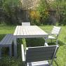 Garden furniture set with table, chairs and bench on a lawn.