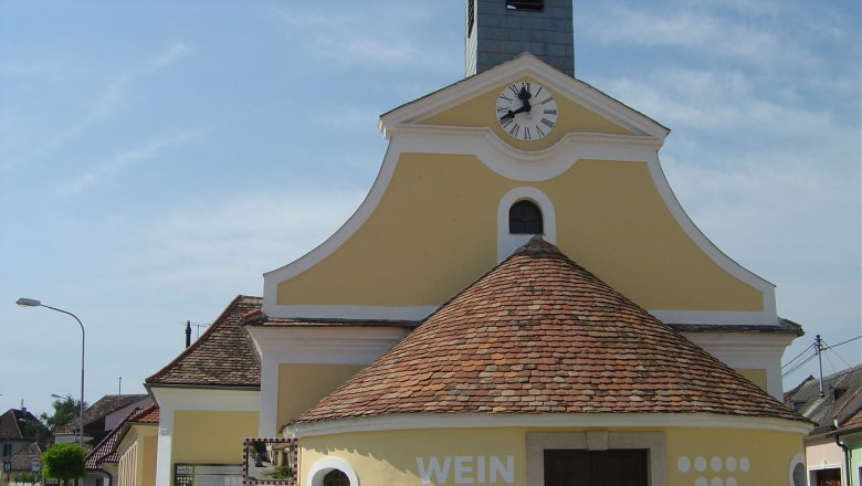 Gelbe Kirche mit Uhrturm und Schriftzug 'Weinkirche' in Jetzelsdorf.