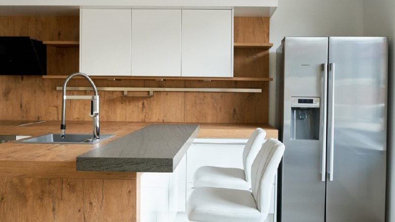 Moderne Küche mit Holz- und Weißtönen, Barhockern und Edelstahlkühlschrank.