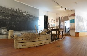 Innenansicht eines Museums mit historischen Fischereigeräten und Wandbildern.