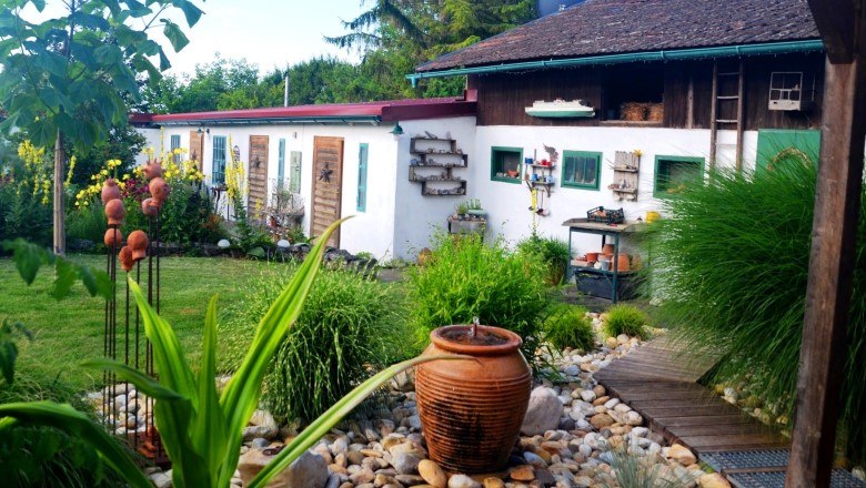 Ein idyllischer Garten mit Keramikdekorationen und einem weißen Gebäude im Hintergrund.