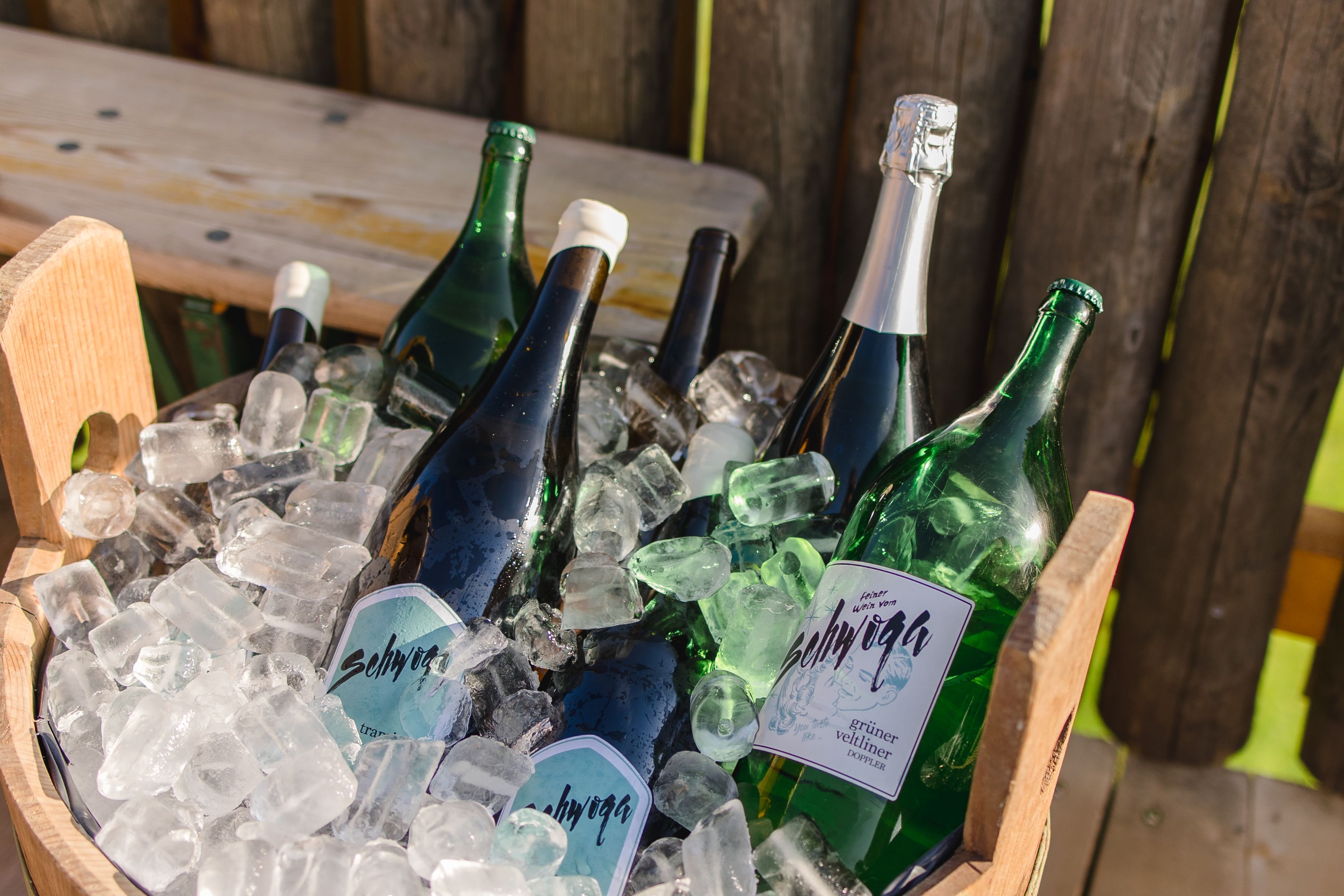 Several bottles of wine in a wooden bucket with ice.