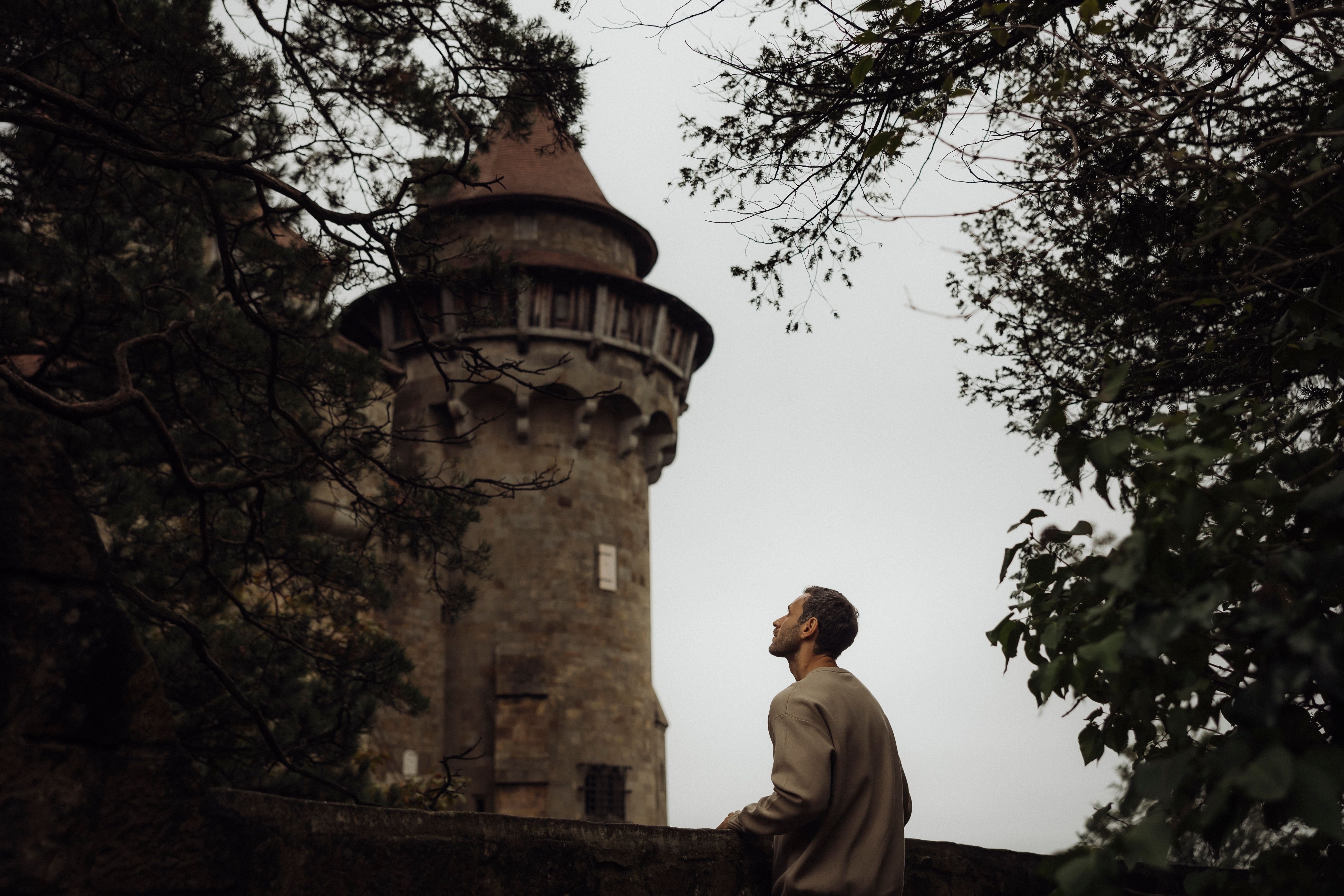 Man looking at Kreuzenstein Castle through trees.