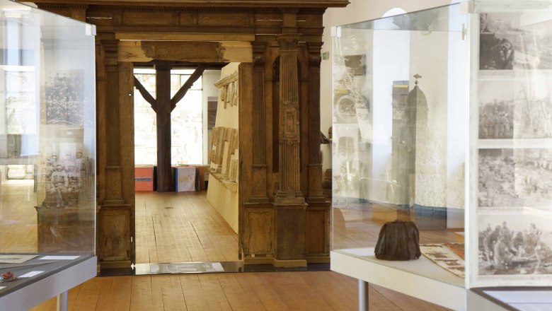 Innenansicht eines Museums mit Holztüren und Vitrinen.