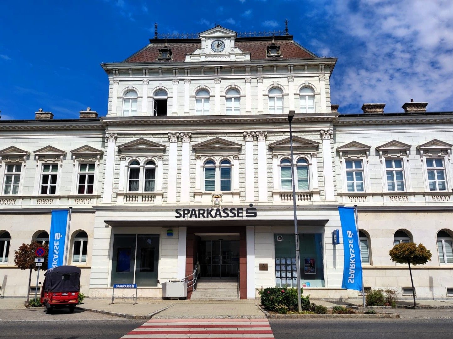 Historická budova spořitelny v Haugsdorfu s klasicistní fasádou a hodinami na střeše.