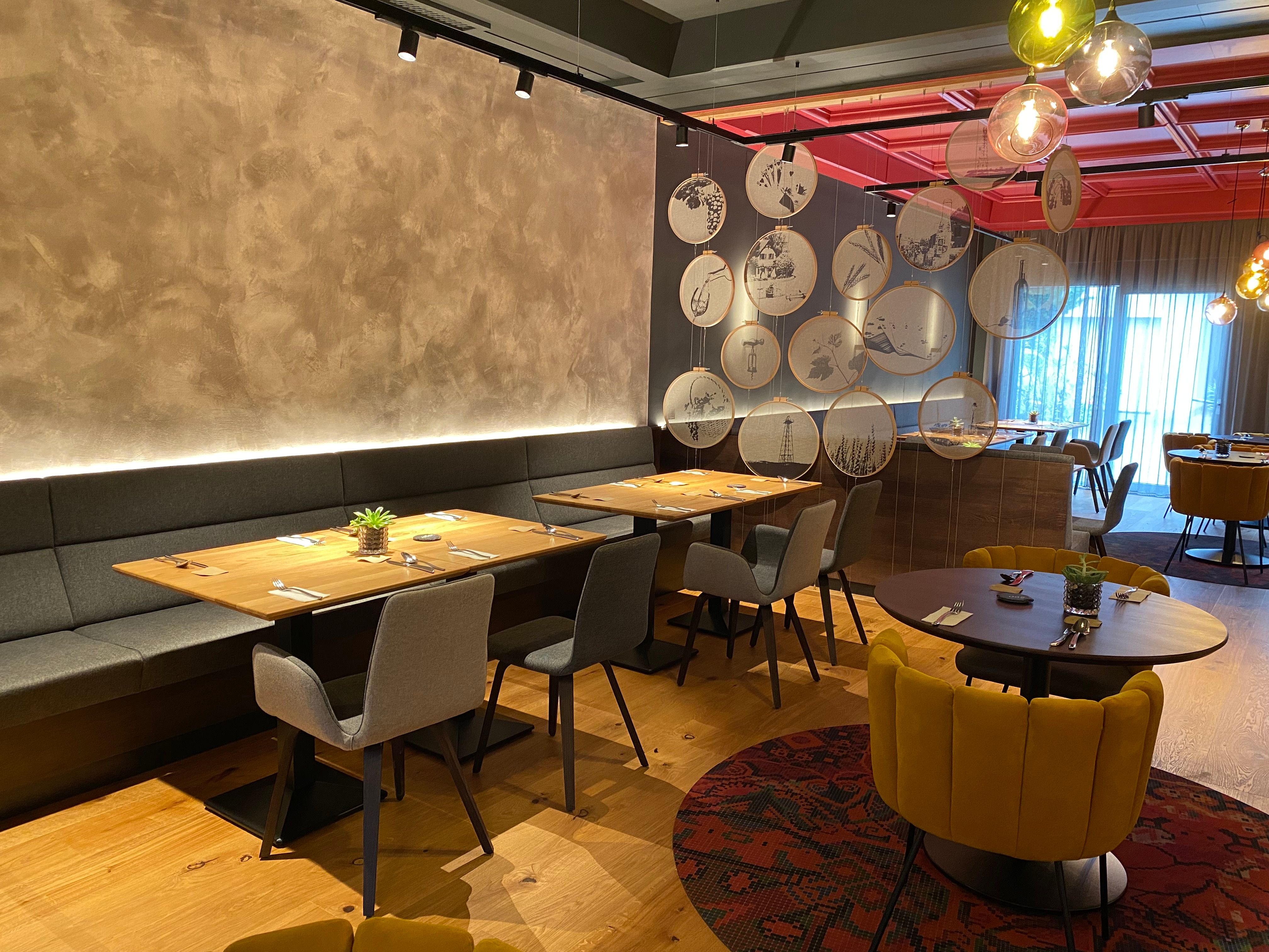 Moderní restaurace se stylovým nábytkem a dekorativními prvky na stěnách.