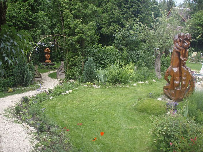 Ein grüner Garten mit Skulpturen und einem geschwungenen Kiesweg.