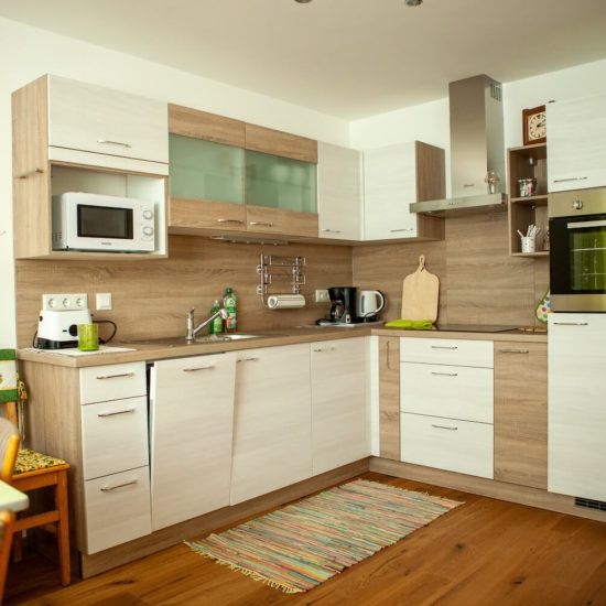 Moderne Küche mit Holz- und weißen Schränken, Mikrowelle, Kaffeemaschine und Ofen.