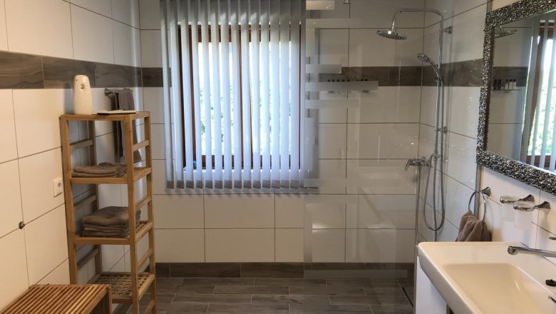 Modernes Badezimmer mit Dusche, Waschbecken, Spiegel und Regal.
