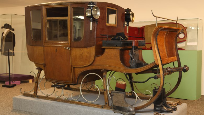 Ein antiker Reiseschlitten aus Holz mit Laternen, ausgestellt in einem Museum.