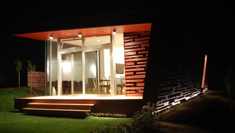 Modern building at night with illuminated terrace and glass front.