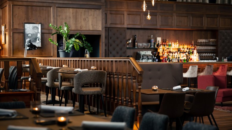 Elegantes Restaurant mit Holzmöbeln, Bar und gedämpfter Beleuchtung.