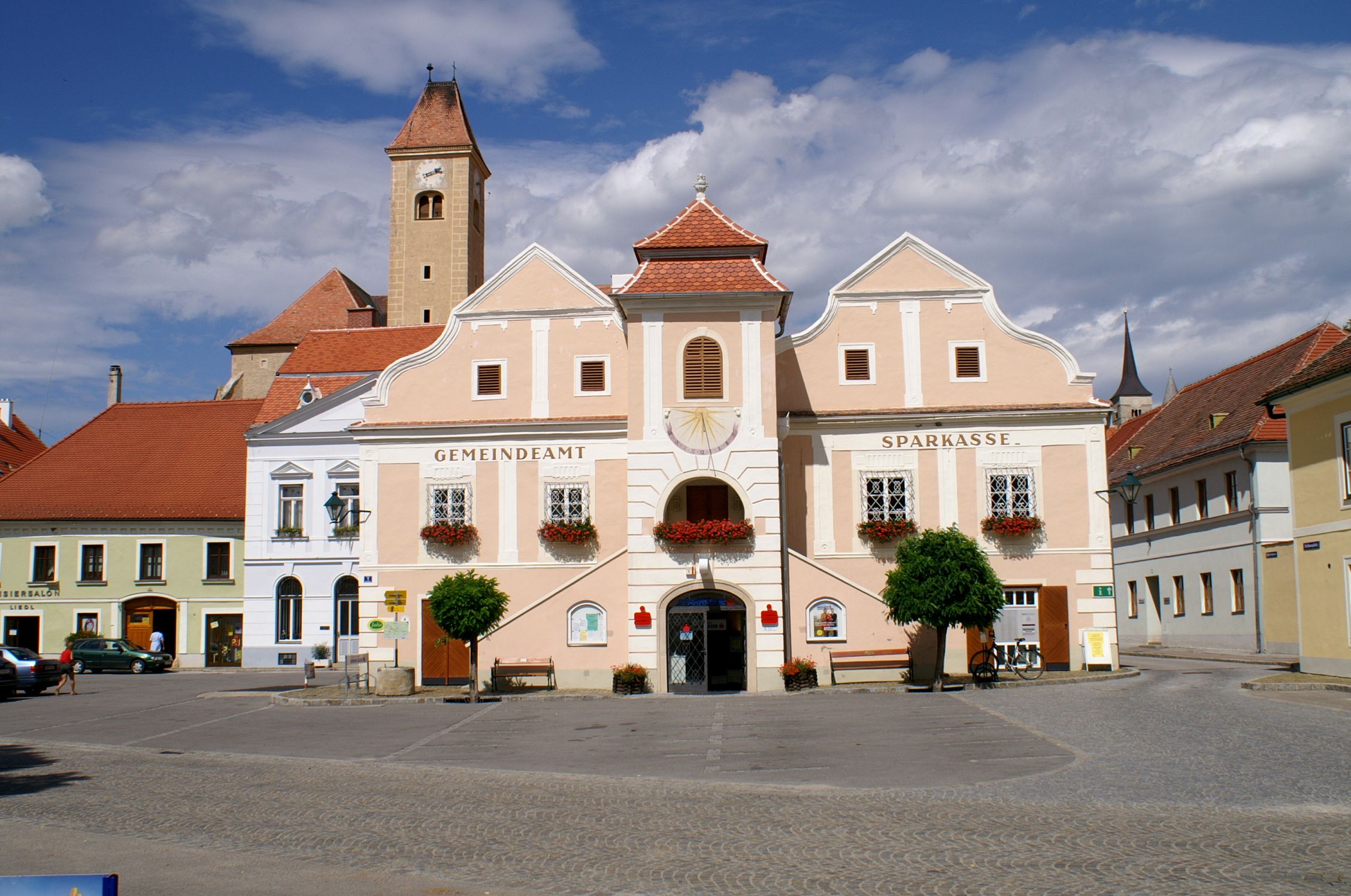 Historisches Gebäude in Pulkau mit Uhrturm und blumengeschmückten Fenstern.