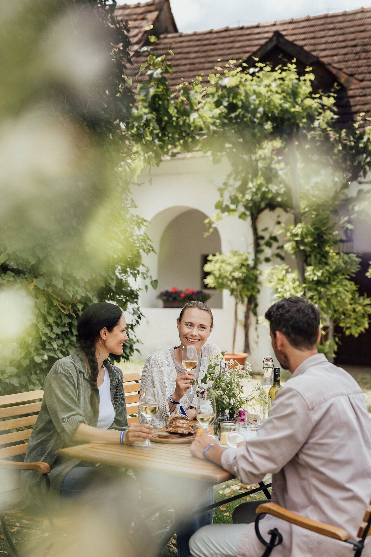 Inmitten der sanften Hügel des Weinviertels genießen Freunde eine gesellige Weinverkostung. Umgeben von üppigem Grün und blühenden Pflanzen, stoßen sie fröhlich mit Gläsern an und lassen sich von regionalen Köstlichkeiten verwöhnen. Die Atmosphäre ist entspannt und einladend, perfekt für einen unvergesslichen Tag im Weinfrühling.
