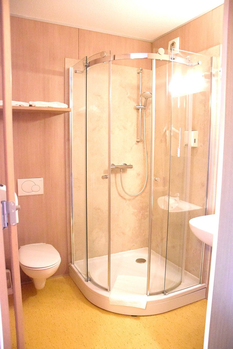 Kleines Badezimmer mit Dusche, Toilette und Waschbecken.