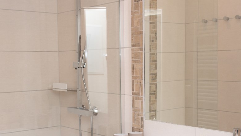 Modernes Badezimmer mit Dusche, Waschbecken und Handt&uuml;chern.