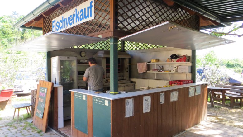 Ein kleiner Fischverkaufsstand im Freien mit einem Mann, der im Inneren arbeitet.