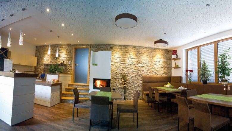 Ein moderner Verkostungsraum mit Holzmöbeln, Steinwand, Kamin und Pflanzen.