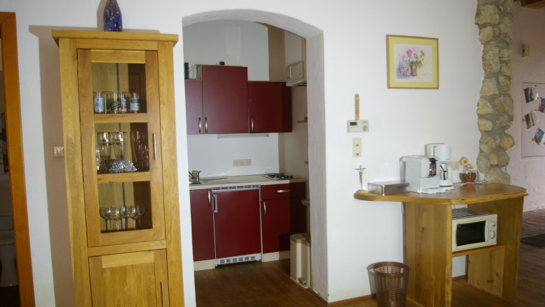 Kleine Küche mit Holzmöbeln, roten Schränken und Kaffeemaschine.