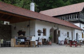 Ein traditionelles Gebäude mit rotem Ziegeldach und Holzelementen, umgeben von Bäumen.