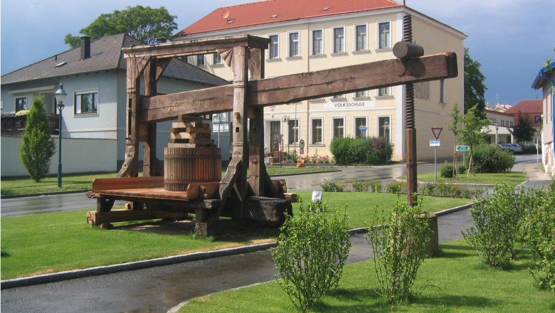 Historic tree press in front of a school building in a green setting.