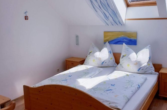 Helles Schlafzimmer mit Holzbett, Dachfenster und blauer Dekoration.