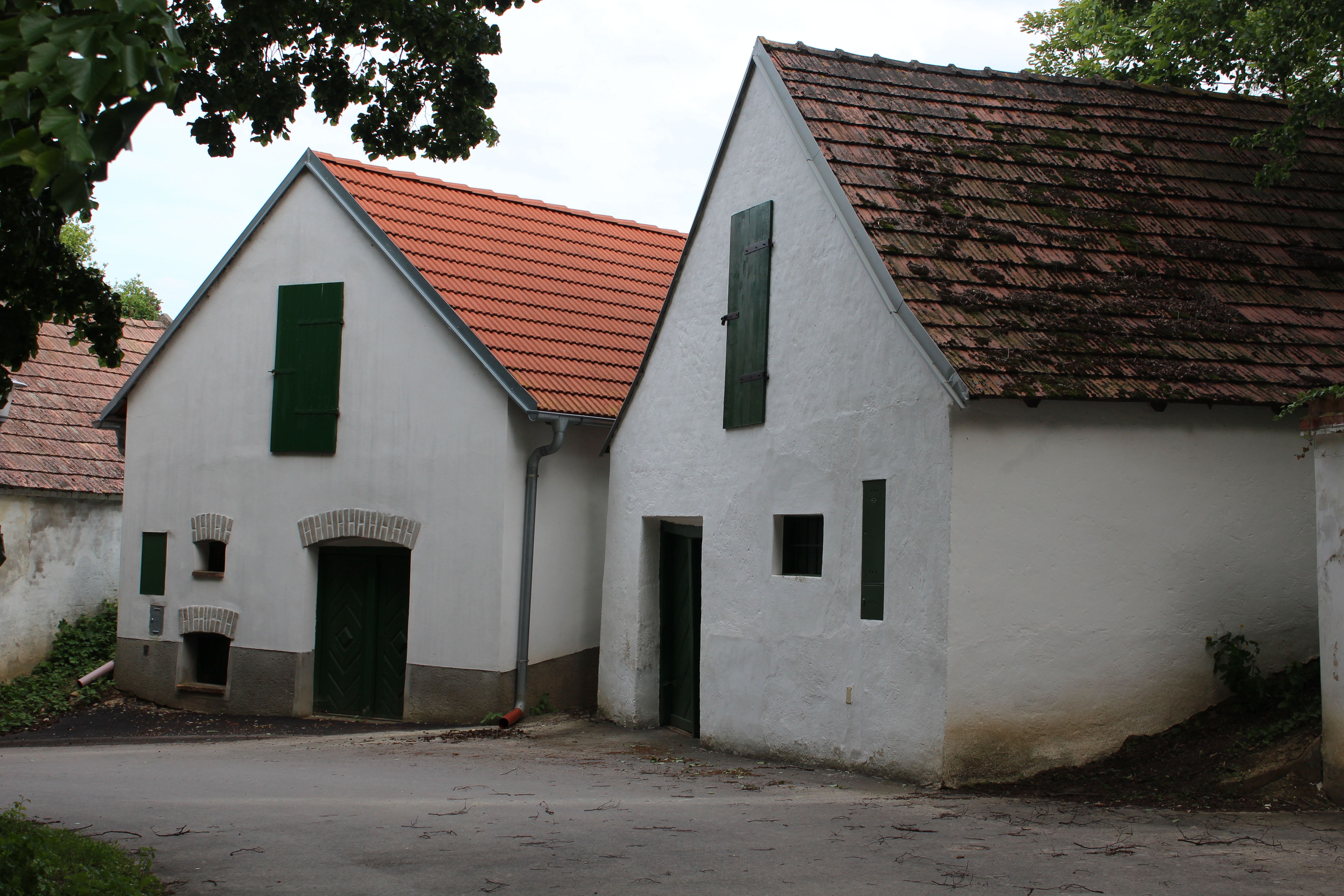 Zwei traditionelle Weinkeller mit weißen Wänden und roten Ziegeldächern in einer Kellergasse.