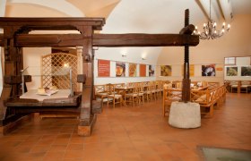 Innenansicht eines traditionellen Heurigenlokals mit Holzmöbeln und einer alten Weinpresse.