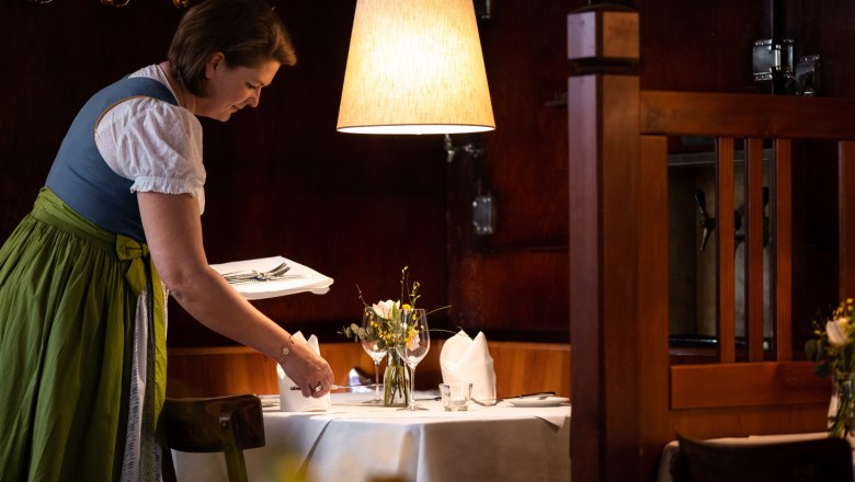 Waitress in traditional costume sets the table in a cozy restaurant.